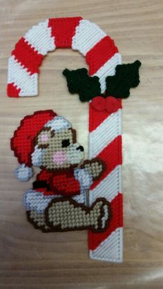 a cross stitch christmas ornament with a teddy bear and candy cane on it