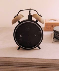 an alarm clock sitting on top of a table next to a stack of books and coasters