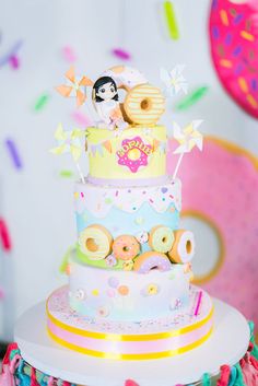 there is a multi layer cake decorated with donuts and sprinkles on the table