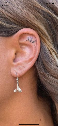 a close up of a person's ear with tattoos on it