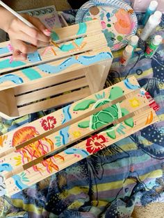 a child's hand is playing with wooden toys on the floor in front of an ocean themed blanket