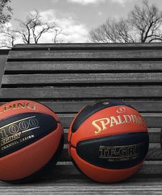 three basketballs sitting on top of a wooden bench