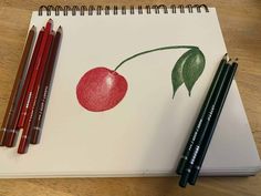 two pencils are next to a drawing of a cherry