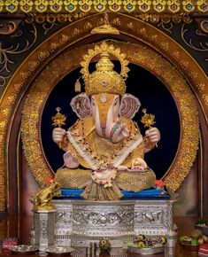 an elephant statue sitting on top of a table in front of a wall with gold decorations