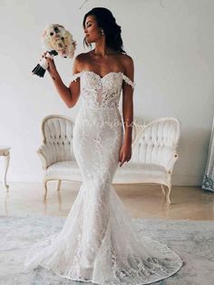 a woman in a white wedding dress holding flowers and looking off to the side with her hand on her hip