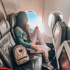 a woman sitting on an airplane seat looking out the window