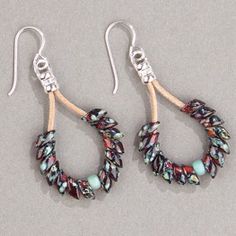 two pairs of earrings with beads hanging from the end of each pair, on a gray surface