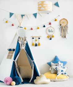 a teepee tent and pillows in front of a wall with some decorations on it