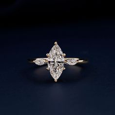 an engagement ring with a pear shaped diamond in the center on a dark background,