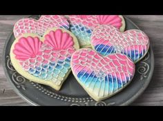 heart shaped cookies decorated with pink and blue icing on a black plate, ready to be eaten