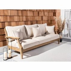 a white couch sitting on top of a wooden floor next to a wall covered in wood panels