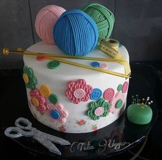 there is a cake decorated with yarn and crochet hooks