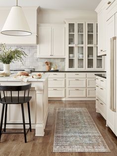 a kitchen with white cabinets and an area rug on the floor in front of it