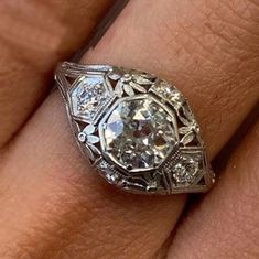 a woman's engagement ring with an old cut diamond in the center, on her finger