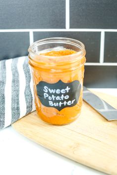 a jar filled with sweet potato butter sitting on top of a cutting board next to a knife