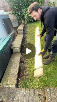 a man is working on something outside in the grass with a hammer and some wood