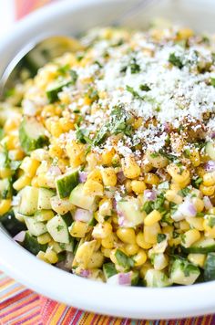 a white bowl filled with corn salad and topped with parmesan sprinkles