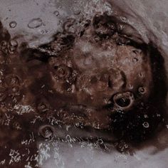 a black and white photo of a child's head in the water with bubbles