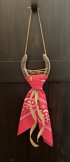 a red bandanna hanging from a hook on a black door with a wooden handle