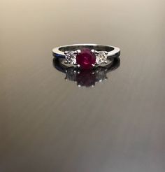 DeKara Designs Collection Classic/Modern Three Stone Diamond Past Present and Future Engagement Ring. Metal- 90% Platinum, 10% Iridium Stones- 1 Round Natural Pigeon Blood Ruby 0.71 Carats, 2 Round Diamonds, G color VS1 clarity, .44 carats. Art Deco Inspired Beautiful Pigeon Blood Red Ruby Three Stone Diamond Engagement Ring Made in Platinum. There is a vibrant and fiery round ruby that is professionally set in between four prongs. There is one round fiery diamond on each side of the the ruby th Luxury Gia Certified White Gold Ruby Ring, Gia Certified Round Cut Ruby Ring Fine Jewelry, Gia Certified Fine Jewelry Ruby Ring In Platinum, Gia Certified Platinum Ruby Ring In Fine Jewelry, Gia Certified Round Cut Ruby Ring, Luxury Ruby Ring With Center Stone For Anniversary, Gia Certified Platinum Ruby Ring, Classic White Gold Ruby Ring With Round Cut, Classic White Gold Ruby Ring With Vvs Clarity