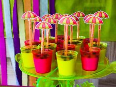 there are many drinks with umbrellas in the cups on this tray, and one is red