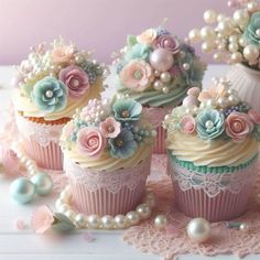 cupcakes decorated with pastel flowers and pearls on lace doily next to vase