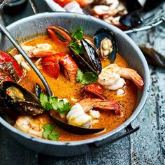 a bowl filled with seafood and mussels on top of a wooden table