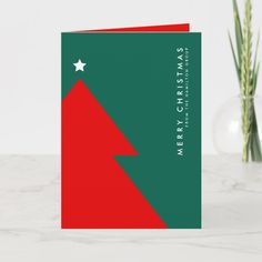 a green and red christmas card sitting on top of a table next to a potted plant