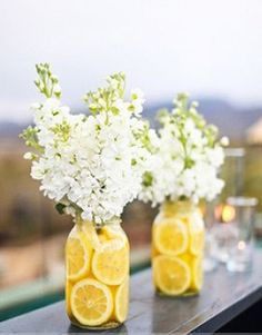 two mason jars with lemons and baby's breath are sitting on a balcony