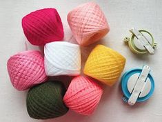 several balls of yarn are sitting next to some crochet hooks and tape dispensers