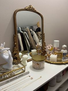 a mirror sitting on top of a white table next to a shelf filled with items