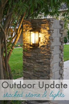 a light that is on in the side of a stone wall next to a tree