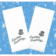 two white towels with the words seasons greetings and a top hat on them in front of snow flakes