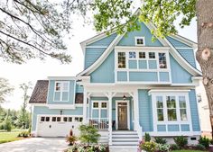 a blue house with white trim and flowers in front