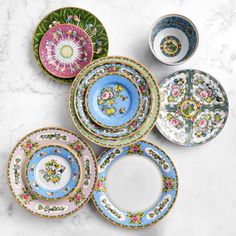 six plates with different designs on them sitting on a marble counter top next to each other