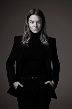 a woman in a black suit posing for a photo with her hands on her hips