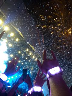 someone holding their cell phone up in the air at a concert with fireworks and confetti