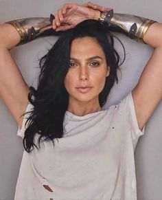 a woman in white shirt holding her hands on top of her head and looking at the camera