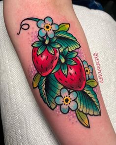 a colorful tattoo with two strawberries on it's arm and flowers in the background