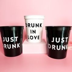 three plastic cups with the words drunk in love and just drunk written on them sitting on a pink surface