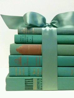 a stack of books with a bow tied around the book ends on top of each other