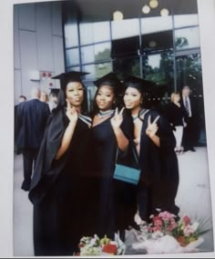 three women in graduation gowns posing for a photo with one woman giving the peace sign