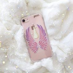 a pink phone case with an angel wing on it sitting on some white furnishing