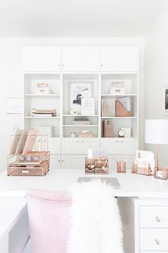 a white desk topped with lots of shelves filled with boxes and baskets next to a pink chair