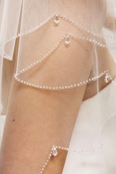 a close up view of the back of a woman's dress with pearls on it