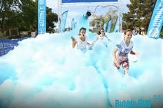 two people running through foam in the middle of an obstacle course