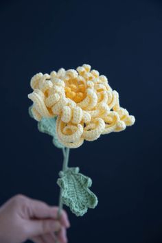 a crocheted flower being held by someone's hand with the petals still attached