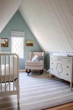 a baby's room with blue walls and white furniture