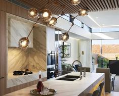 a modern kitchen with marble counter tops and pendant lights