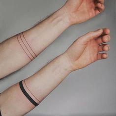 two hands with wristbands on each arm and one has a small tattoo on it